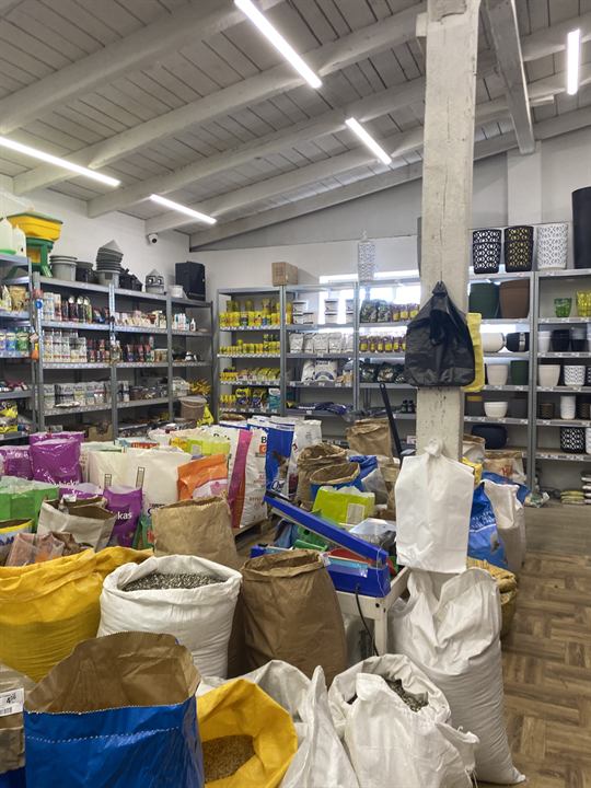 Worki ze zbożami i nasionami oraz regały z karmami i doniczkami
